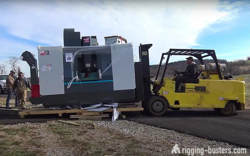 Heavy forklift moving a CNC machining centre across a yard