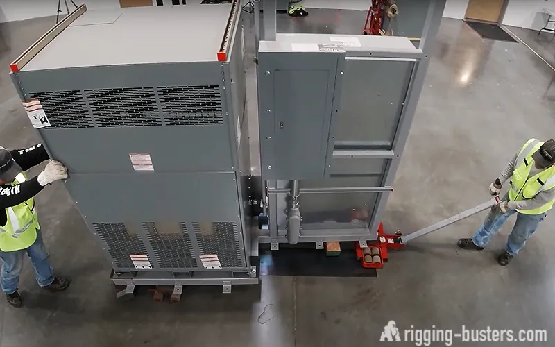 Electrical cabinet moved on machinery skates by two riggers