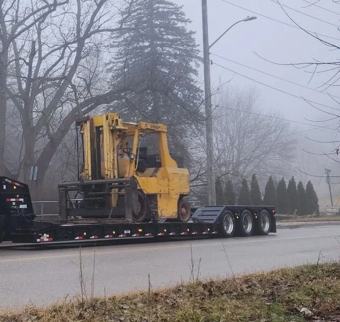 Industrial forklift loaded on a lowboy trailer for transport