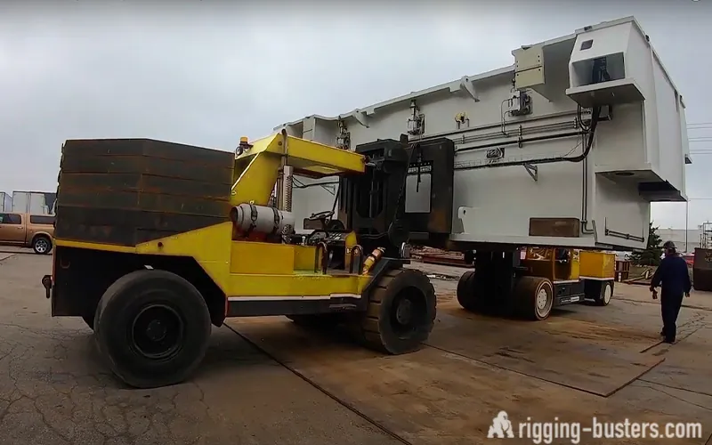 Heavy-capacity lift truck carrying a large machine enclosure outdoors