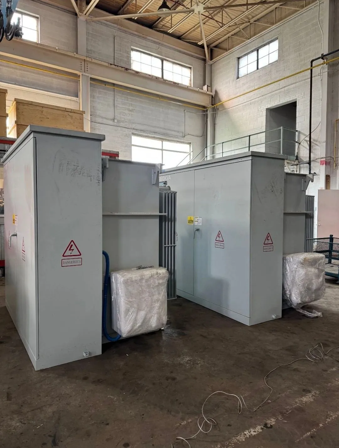 Two pad-mounted transformer units staged inside an industrial building